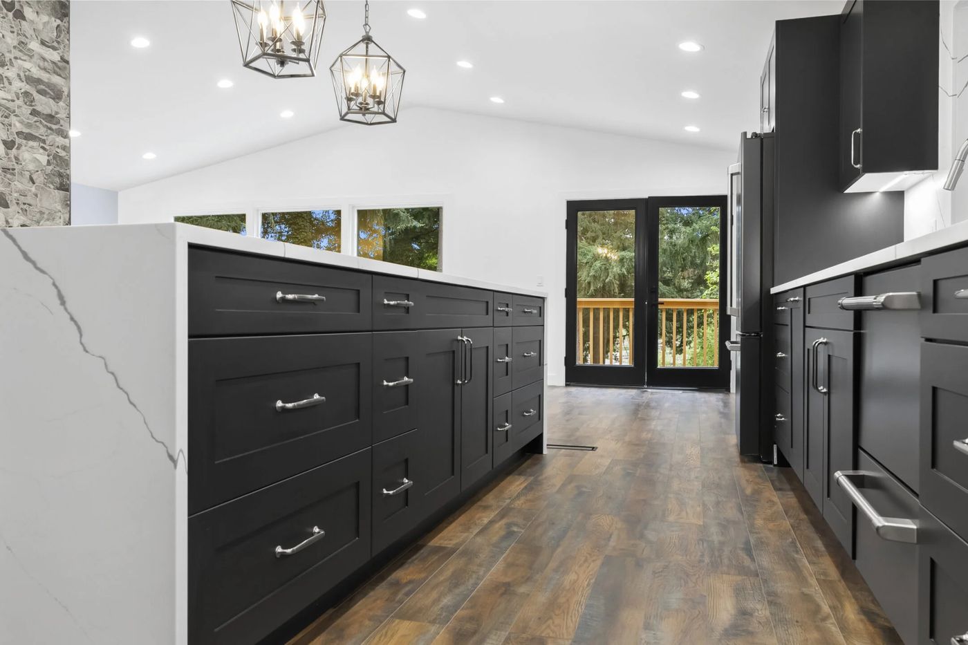 Dark cabinets and a marble island in a bright addition