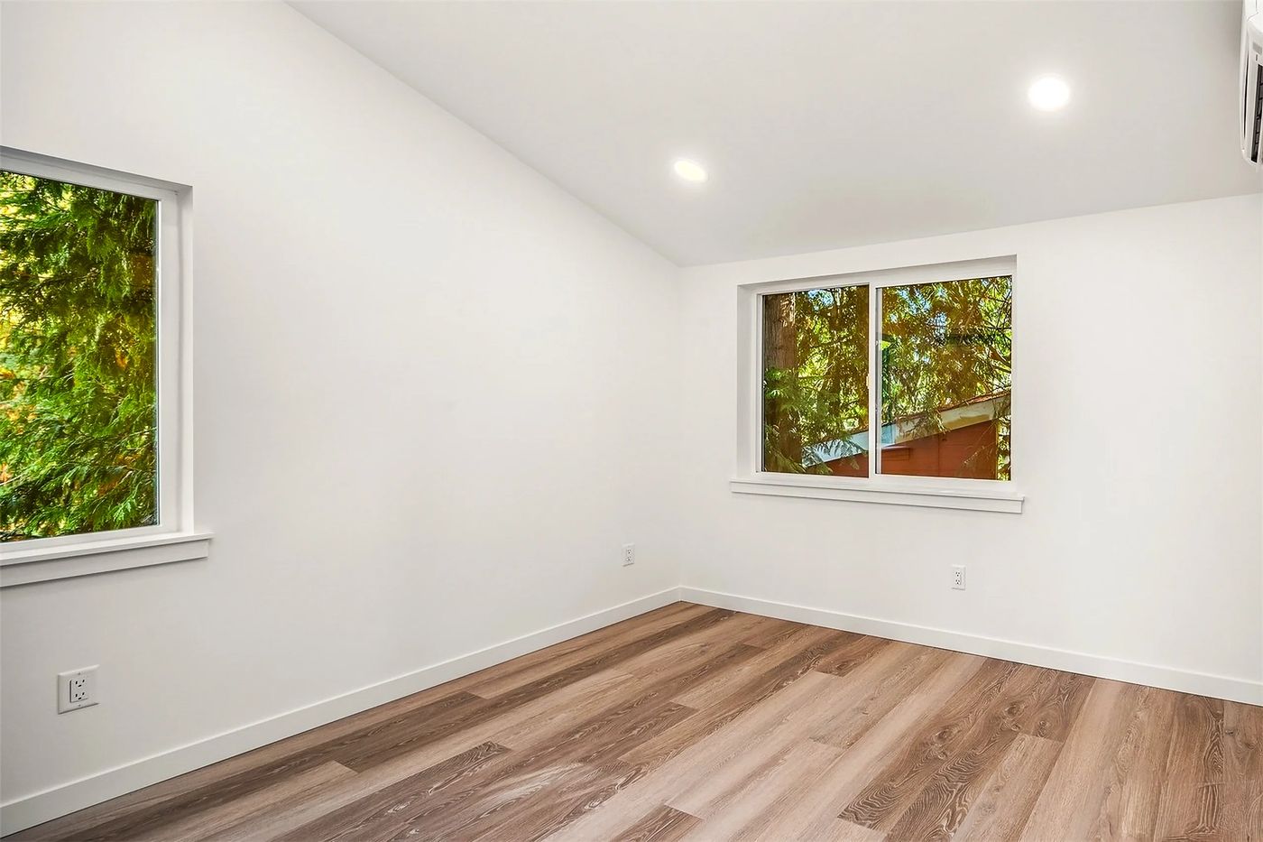 Empty bedroom with oak floors and a view of the trees