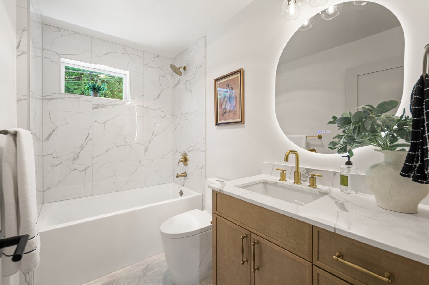 Bathroom with a marble-look tub surround and an oval mirror