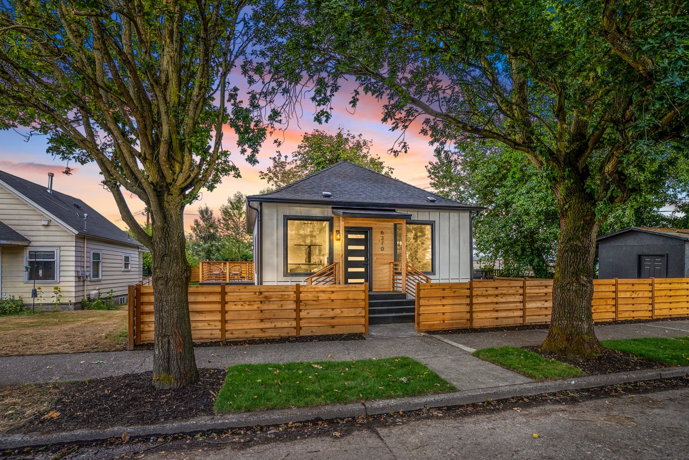Small grey home at dusk behind a horizontal cedar fence, Ellis Ave, Seattle