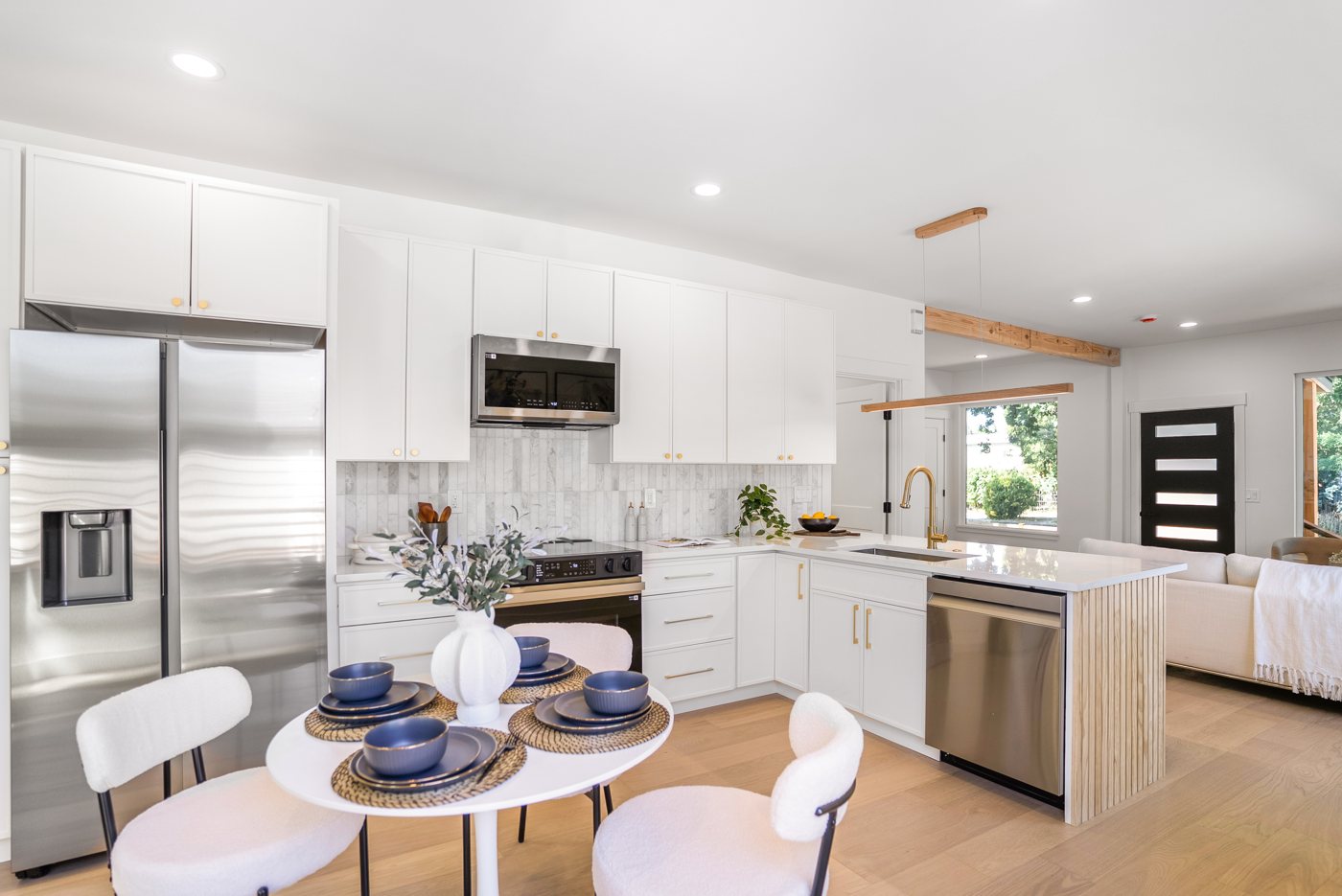 White kitchen with a round dining table and stainless appliances