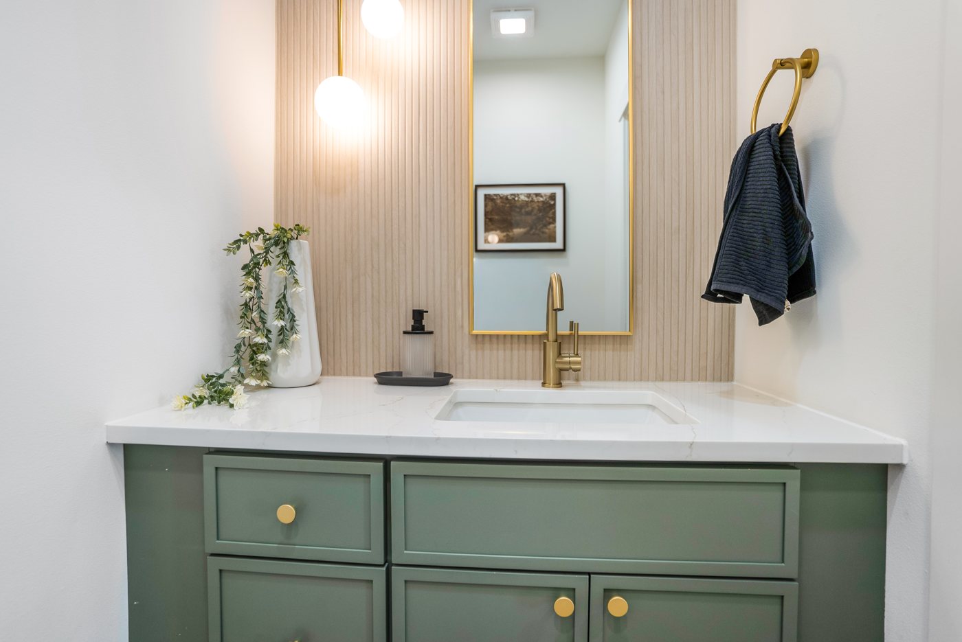 Bathroom with a sage vanity and a wood slat wall