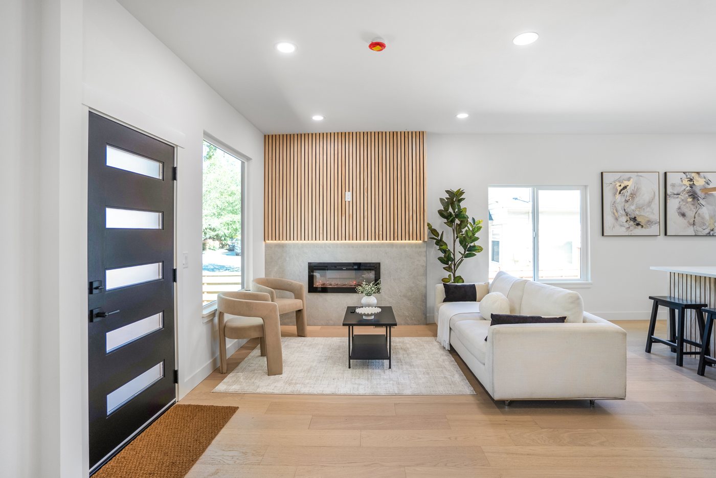 Living room with a black entry door and a wood slat fireplace wall