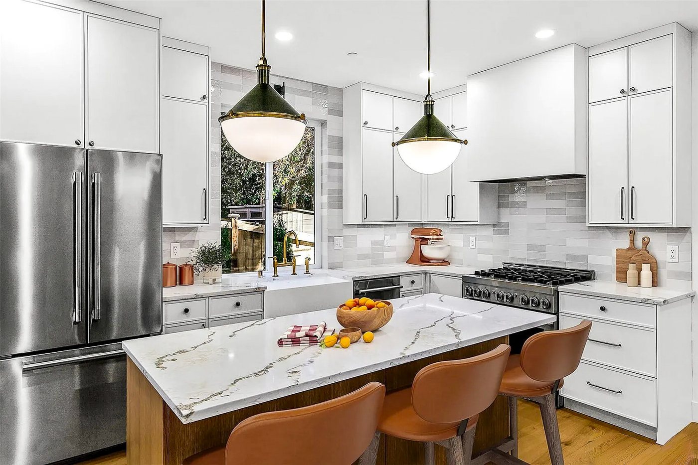 White kitchen with a marble-look island, black pendants and leather stools