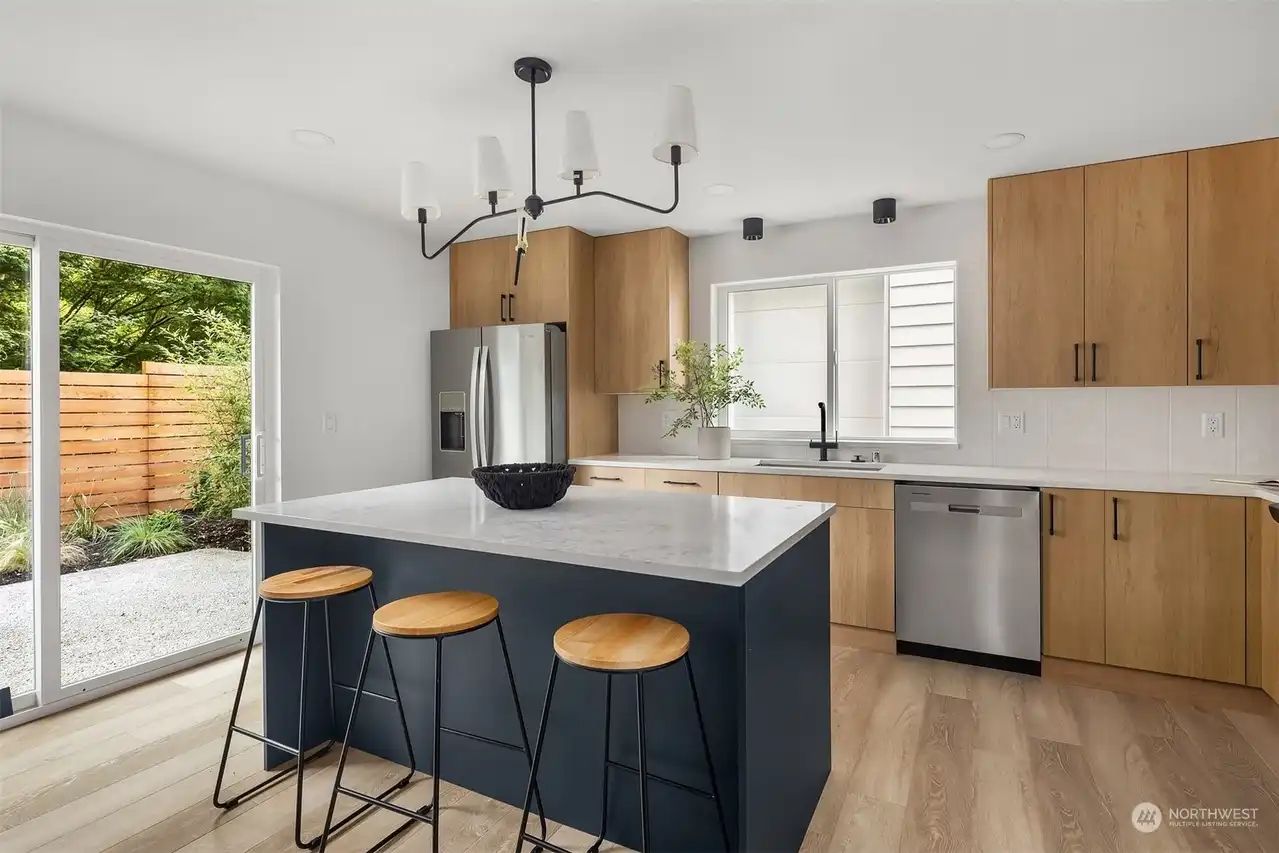 Kitchen with a navy island, wood uppers and stools