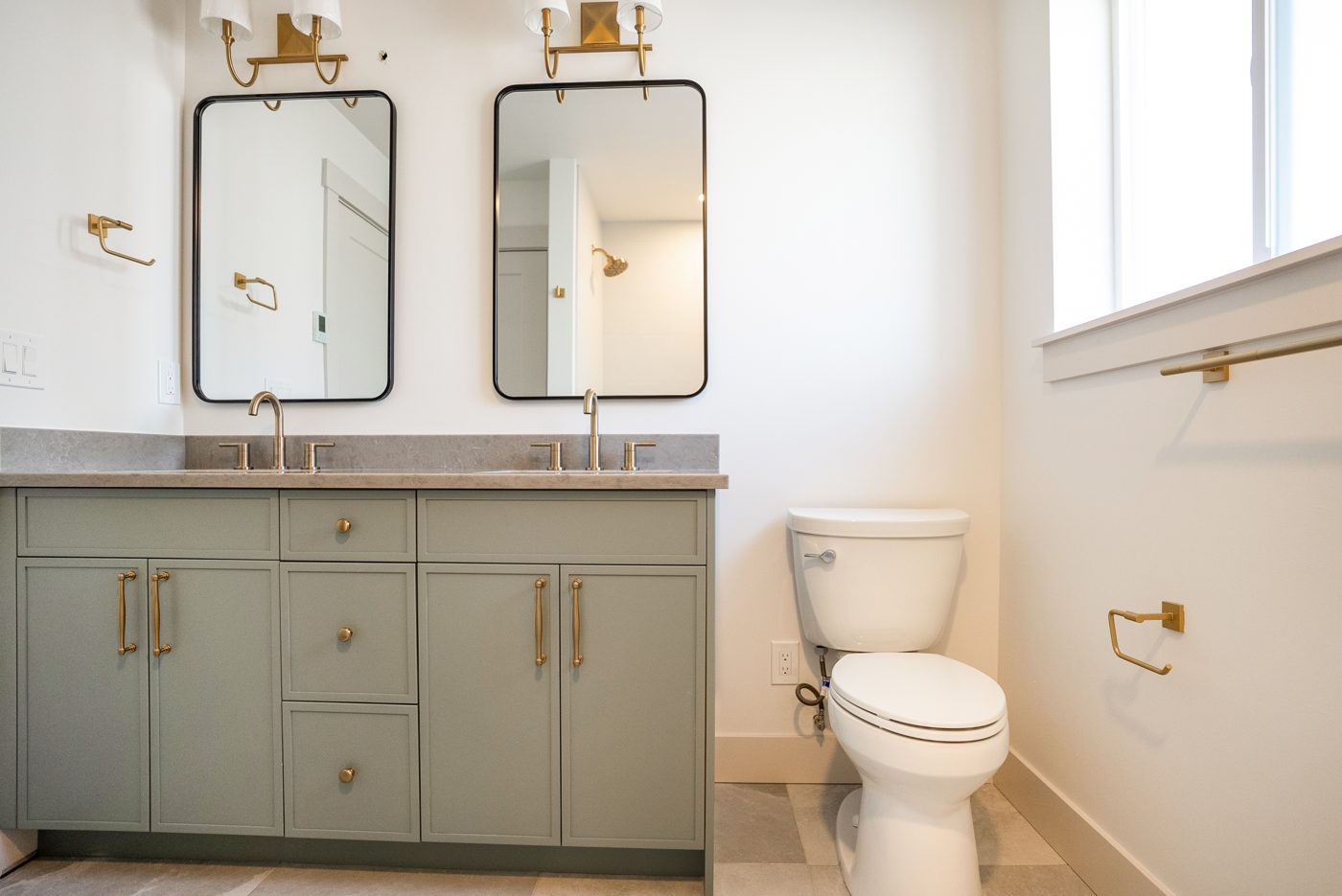 Bathroom with a double vanity in sage green and brass