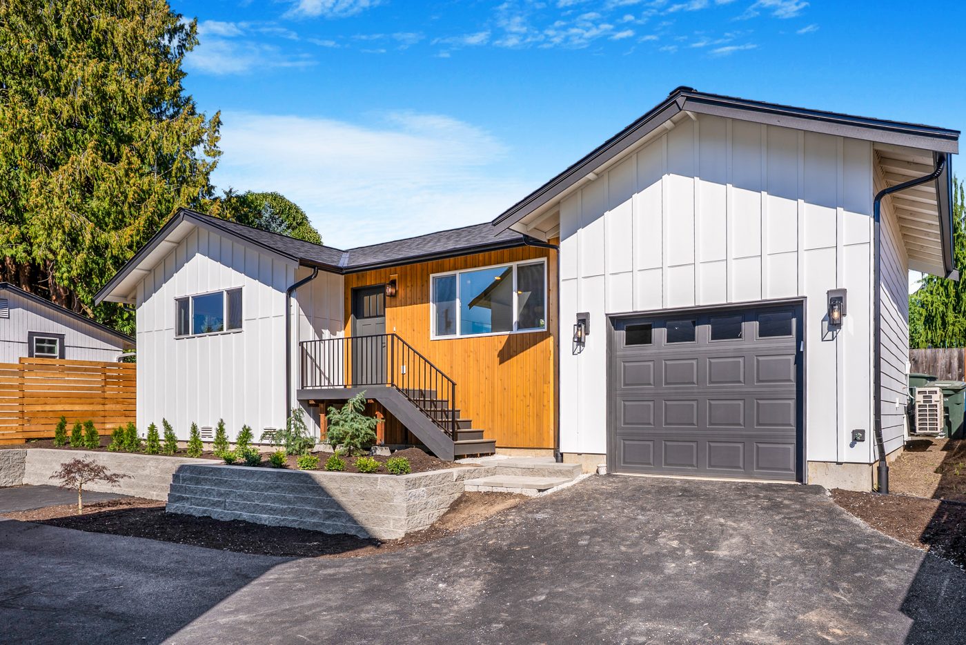 Three-quarter view of the backyard home with the entry stairs and garage door