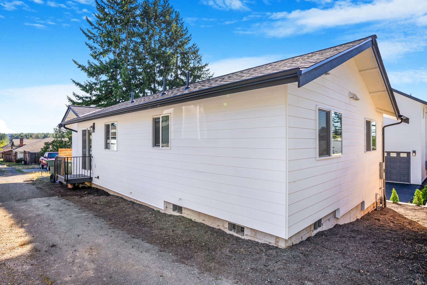 Side of the backyard home with lap siding and the original house beyond