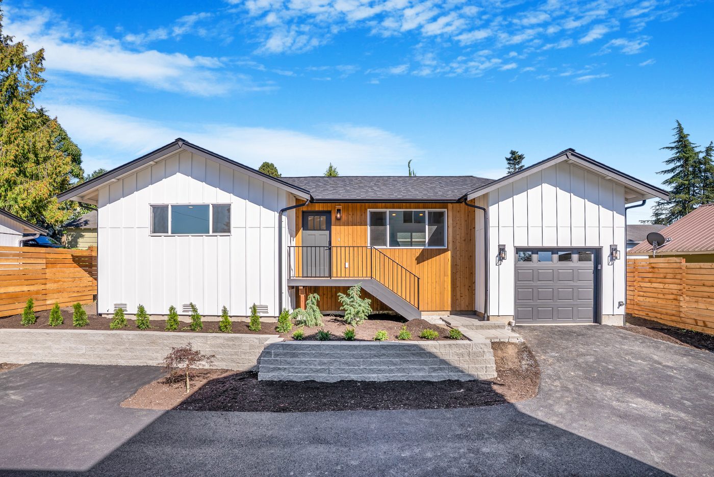 Single-level white board-and-batten backyard home with a cedar entry and an attached garage
